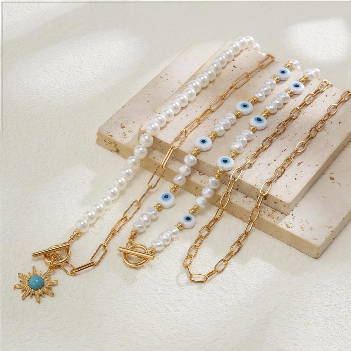 Flatlay of Cosmic Energy pearl and sun trio necklaces – celestial themed jewelry